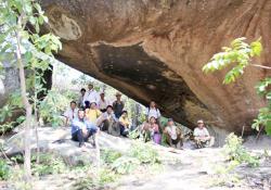 The research group poses below a wall covered in stone age paintings